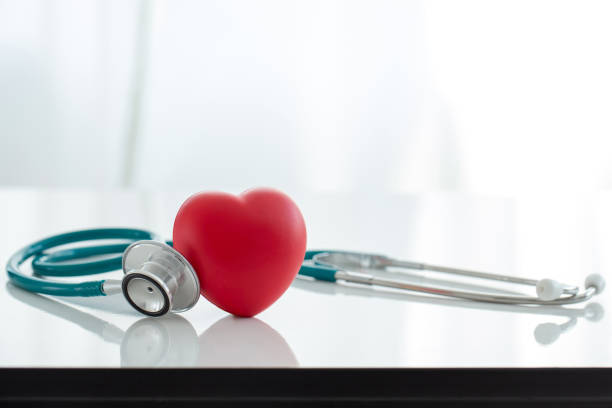 Red heart love shape hand exercise ball with doctor physician's stethoscope on white background: Hospital life insurance concept: World heart health day. doctor day, world hypertension day